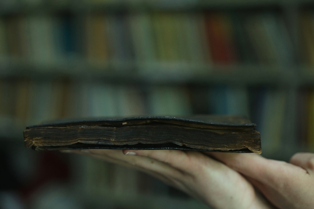 Still från film närbild på händer som håller en skadad bok