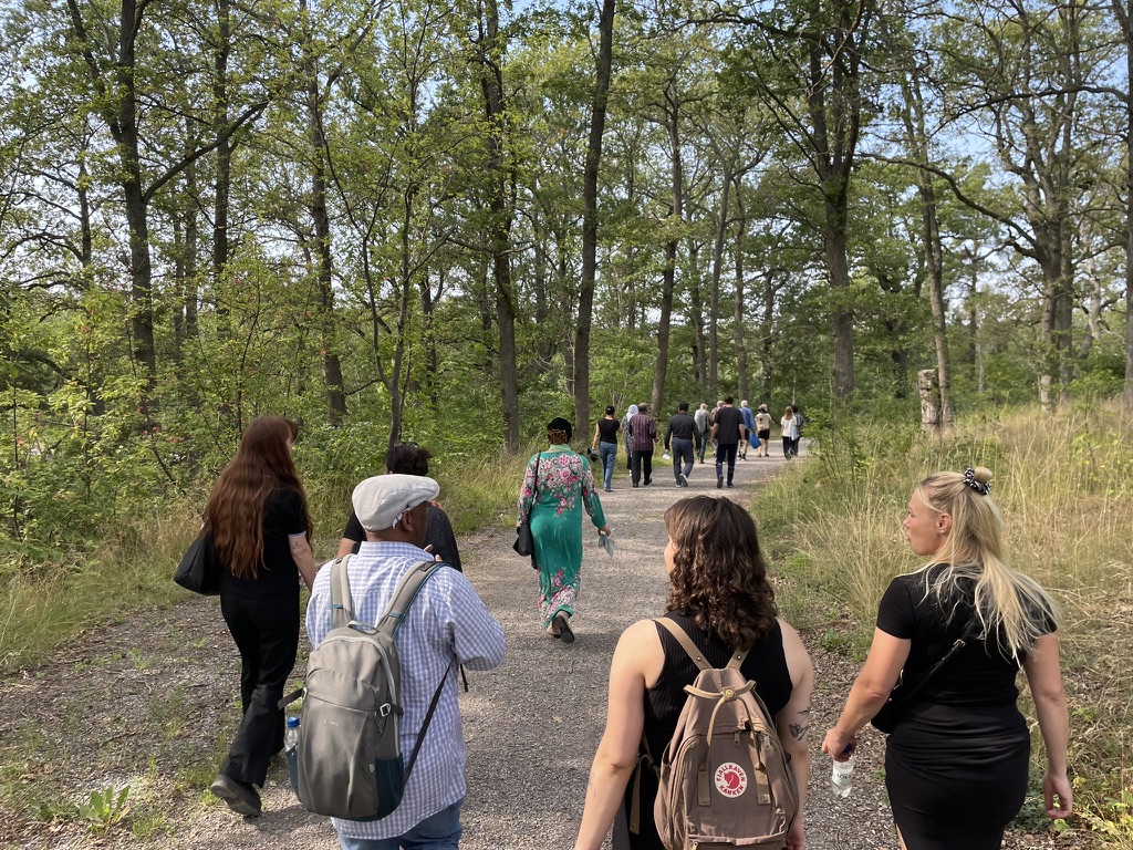 En grupp människor promenerar i naturen och samtalar