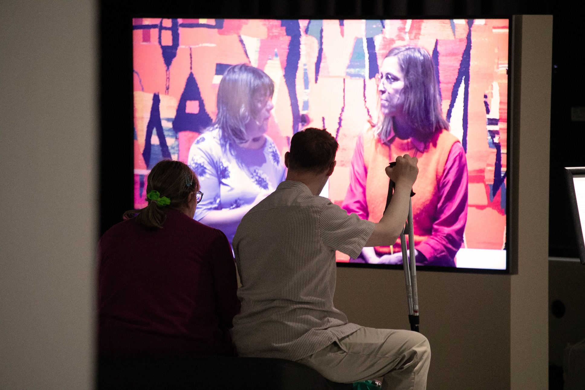 People watching a film in an exhibition space.
